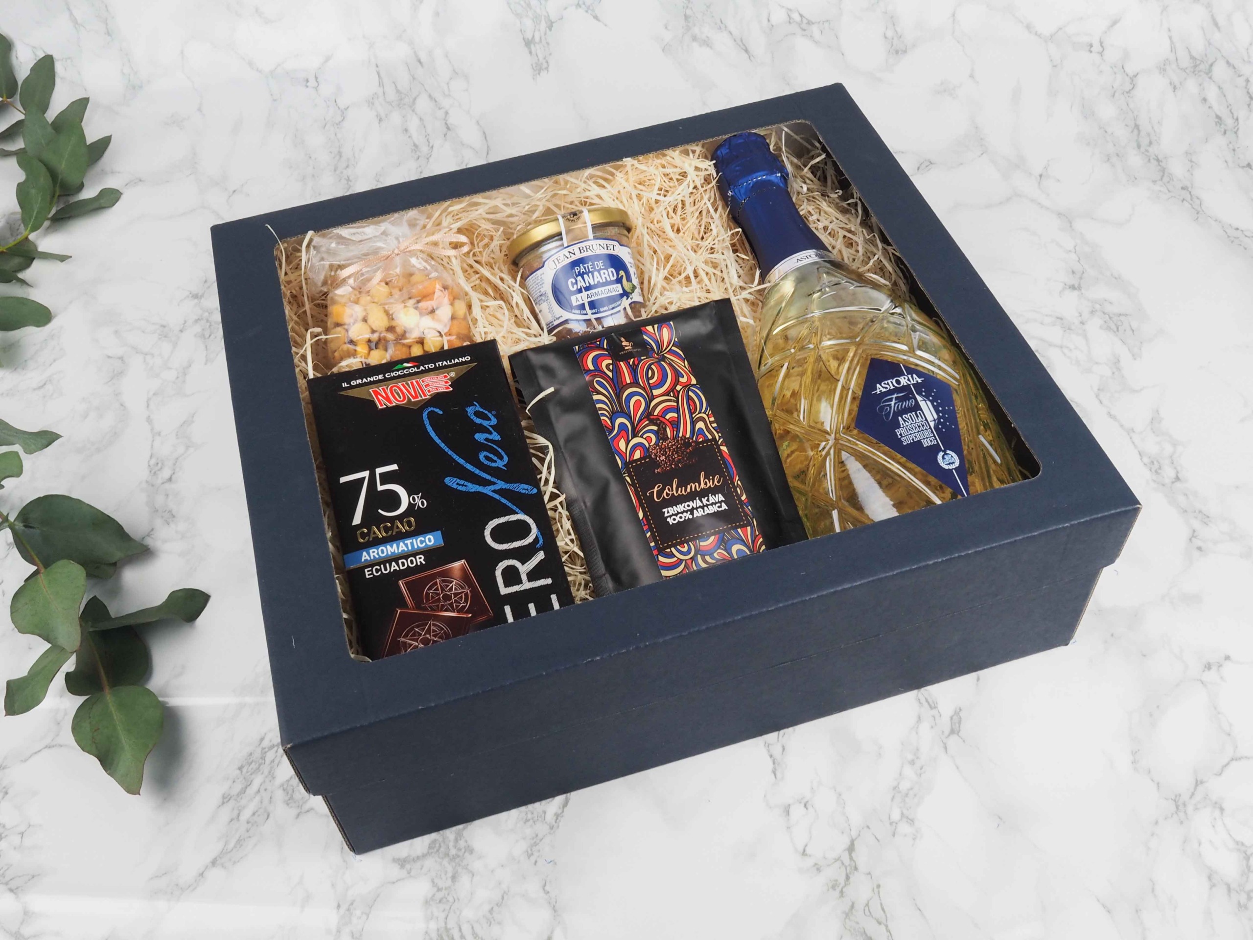 Dárkový balíček Blue Astoria v sobě obsahuje mix oříšků, 70% italskou čokoládu, francouzskou terinu s Armagnacem, zrnkovou kávu Brazílie 100% Arabica a italské prosecco D.O.C. Astoria Superiore.