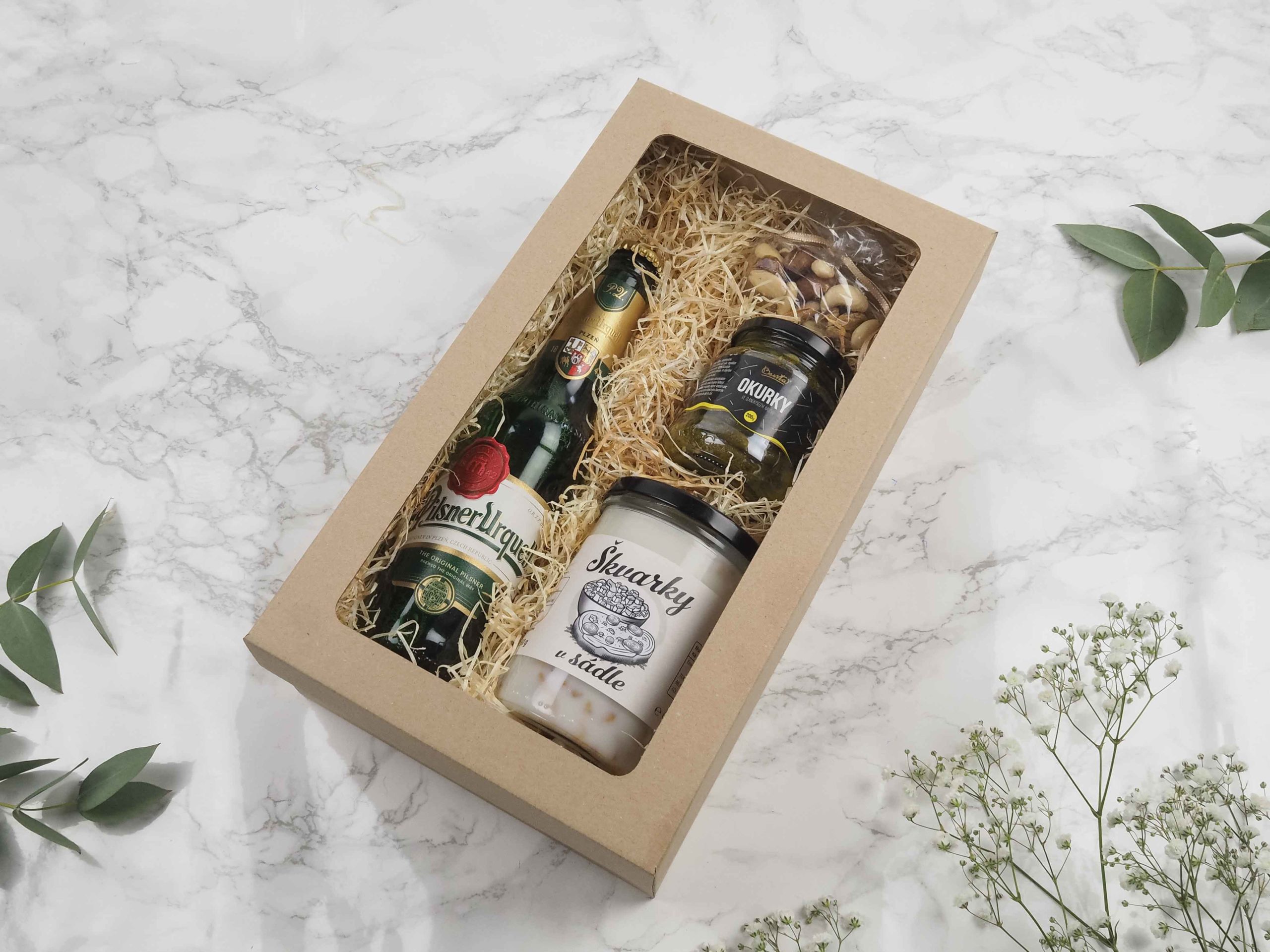 Dárková krabička v sobě ukrývá české pivo Pilsner Urquell, mix oblíbených oříšků, mini okurčičky a škvarky v sádle. Všechny pochutiny jsou baleny v elegantní a ekologické papírové krabičce. Obdarujte s chutí malým degustačním zážitkem.