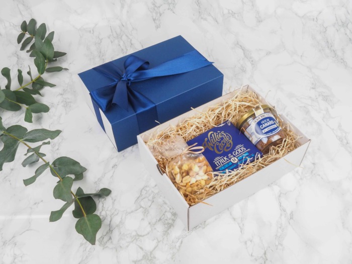 Dárkový balíček Blue Willies je speciální svou elegantní vysouvací krabičkou, kterou zdobí atlasová stuha. Dárková krabice v sobě obsahuje mix oříšků, mléčnou čokoládou a francouzskou kachní terinu s Armagnacem.