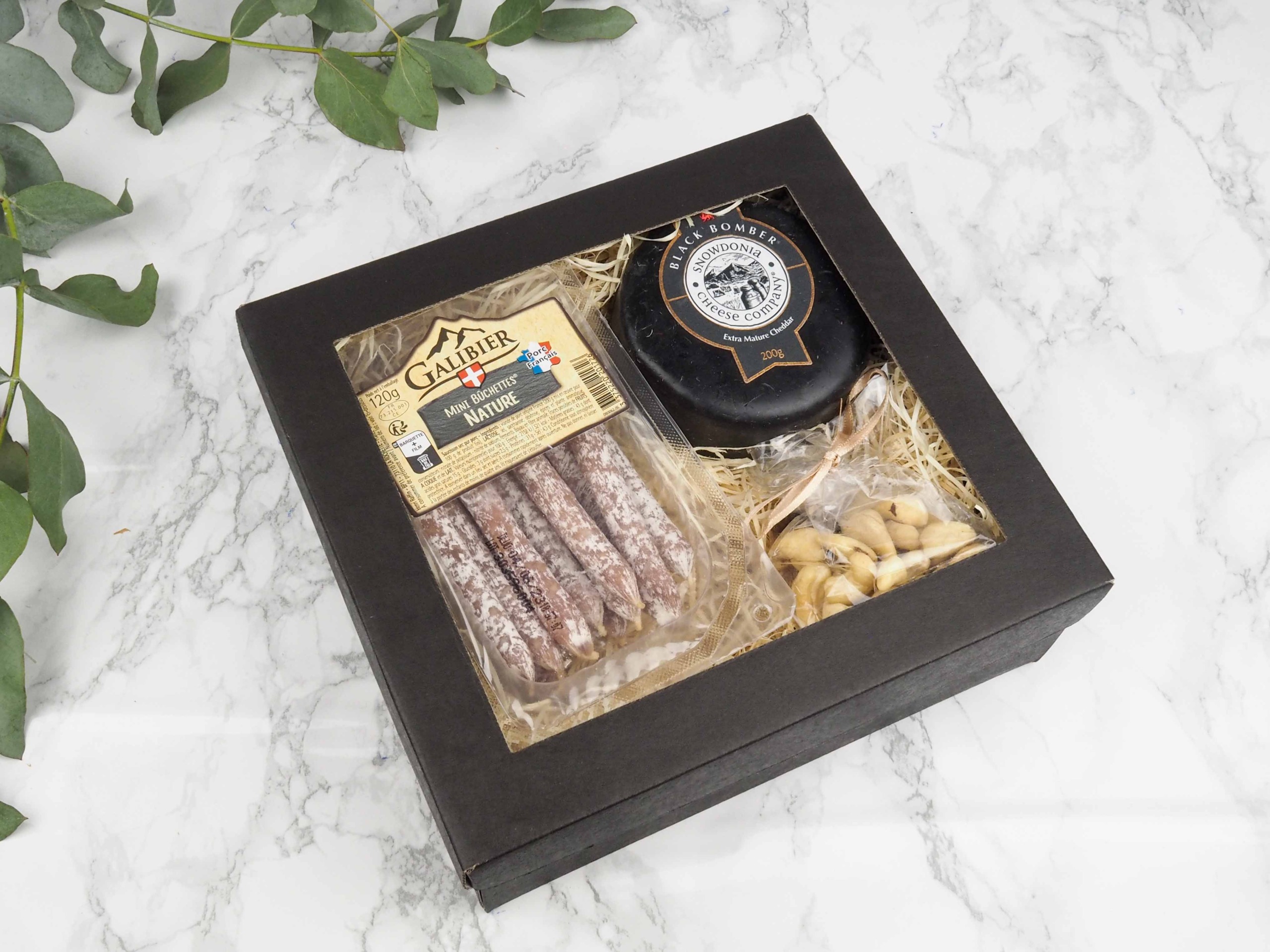 Dárkový balíček Black Nature v sobě obsahuje francouzské minisalámky natur, britský sýr cheddar Black Bomber a mix oříšků.