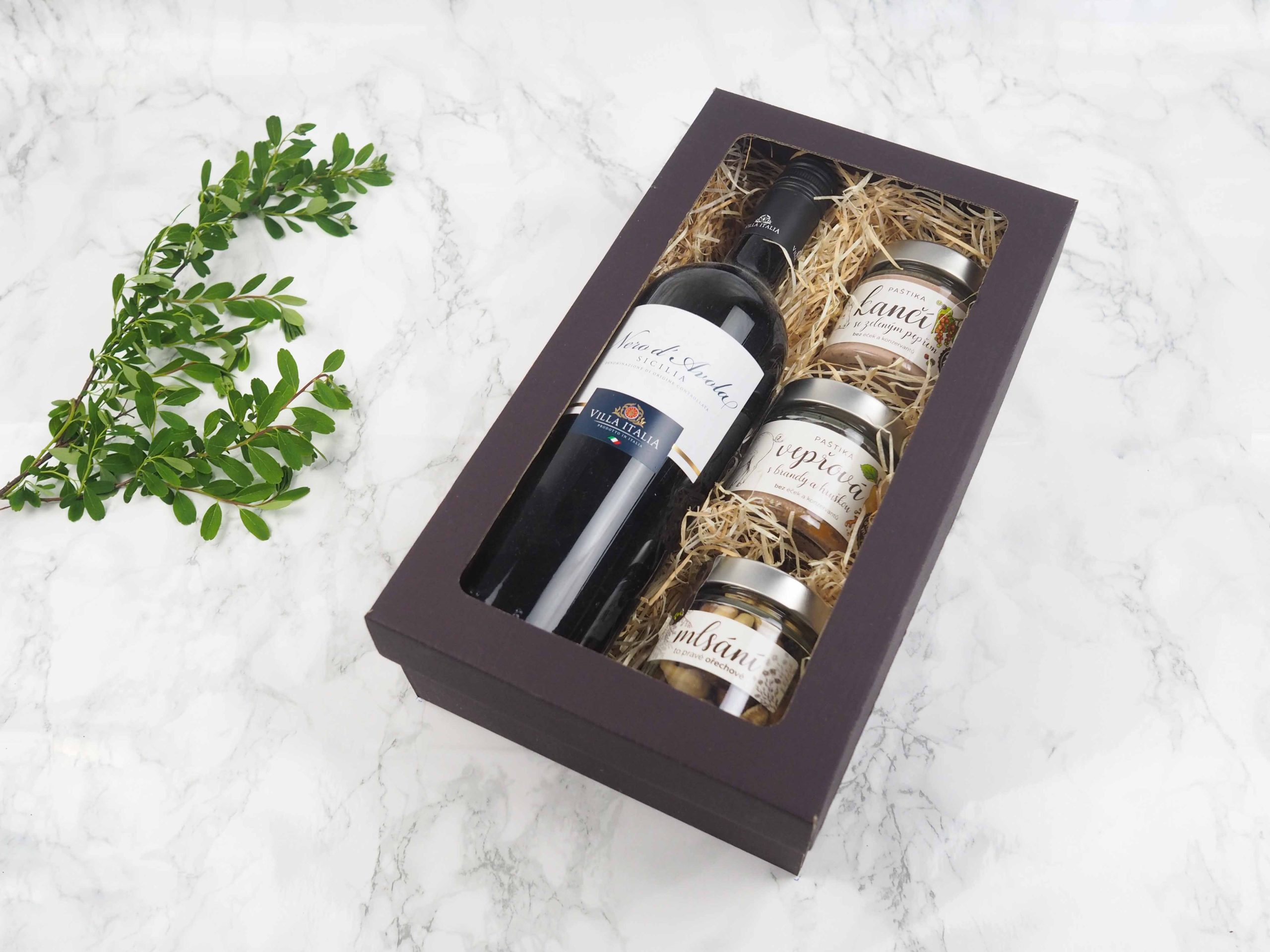 Dárkový balíček Zimní jalovec v sobě obsahuje italské červené víno Nero di Avola, dančí paštiku s jalovcem, vepřovou paštiku s brandy a hruškou a mix pražených oříšků.